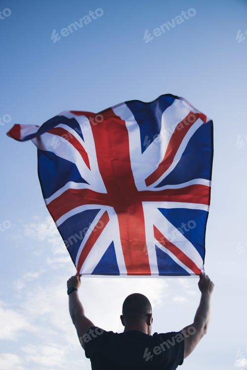 Preview: Man holding British flag against blue sky