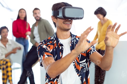 Preview: Front view of happy young caucasian businessman using virtual reality headset in a modern office