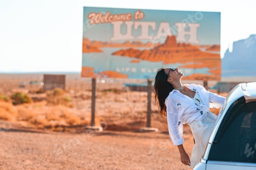 Preview: Beautiful woman on her trip by the car on the background of Welcome to Utah state border sign right