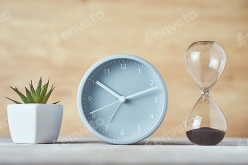Preview: Hourglass, alarm clock and plant on the table, close up