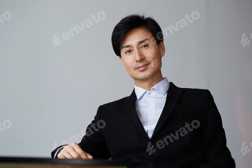 Preview: Portrait of attractive asian businessman on gray wall background.