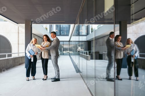 Preview: Business team discussing contract details outside modern office building