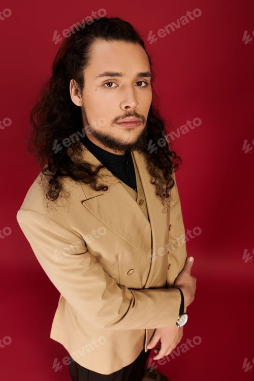 Preview: Handsome young man with beard in stylish attire poses confidently against a bold backdrop