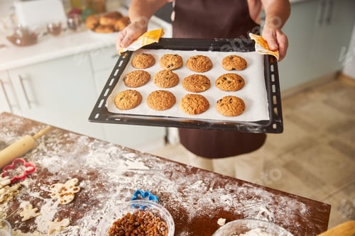 Preview: Skillful baker presenting tray with fresh hot cookies