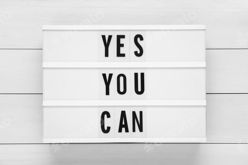 Preview: Lightbox with phrase Yes You Can on white wooden table, top view. Motivational quote