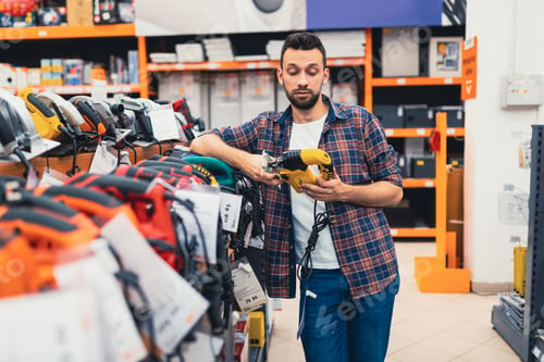 Preview: male customer chooses a woodworking jigsaw in a power tool store
