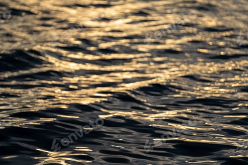 Preview: Abstract ripples on water reflect golden light, creating a fluid