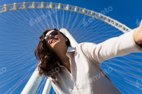 Preview: Happy woman tourist look at one of the largest Ferris Wheels in the World