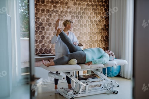 Preview: Mid adult physiotherapist woman exercising with overweight woman indoors in rehabilitation center