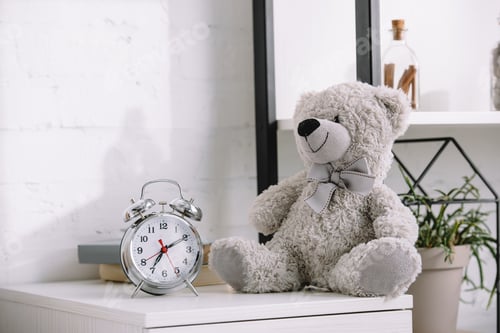 Preview: alarm clock and grey teddy bear on nightstand