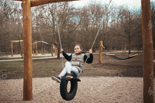 Preview: A girl on the playground plays and has fun riding on a swing