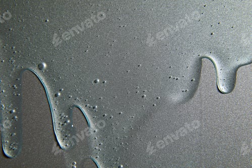 Preview: Blue cream liquid gel serum flows down on silver texture