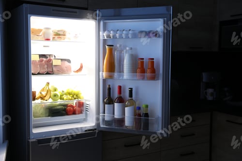 Preview: Open refrigerator full of products in kitchen at night