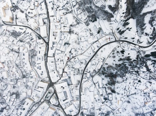 Vista previa: Aerial view of small town with hills in winter.