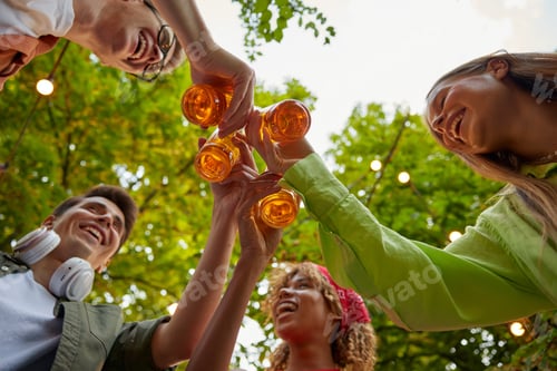 Preview: Happy friends clinking beer bottles view from bottom side