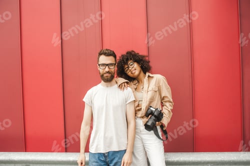 Preview: beautiful stylish young multiracial couple in eyeglasses holding camera