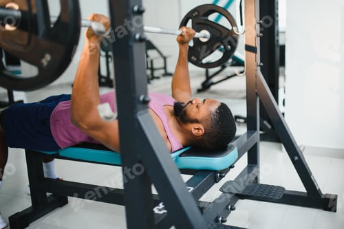 Preview: Weight lifter at the bench press lifting a barbell on an bench.