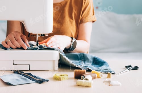 Preview: A woman tailor works at sewing machine sews reuses fabric from old denim clothes