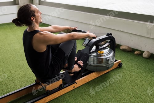 Preview: sportsman training at gym on water rowing machine