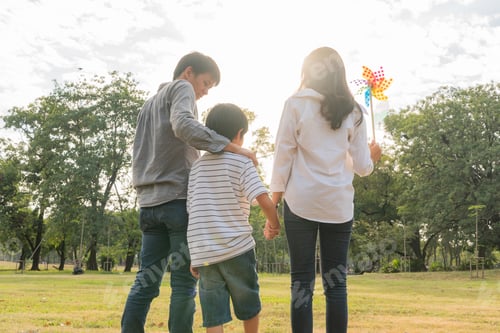 Preview: Back view of happy Asian family walking at park