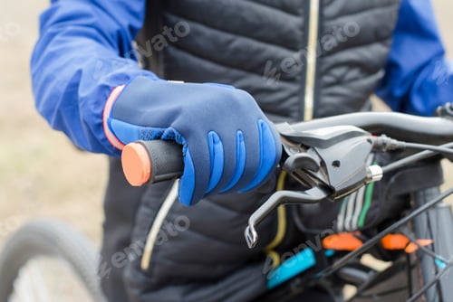 Preview: The hand of a cyclist in sports gloves on the handlebars. Cycling and cycling travel concept