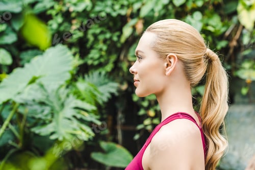 Preview: side view of beautiful young sportswoman relaxing in park after workout