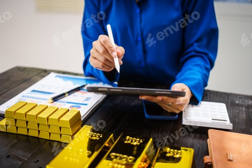 Preview: An Asian business woman sitting at her desk in office,analyzing gold bullion prices,market trends