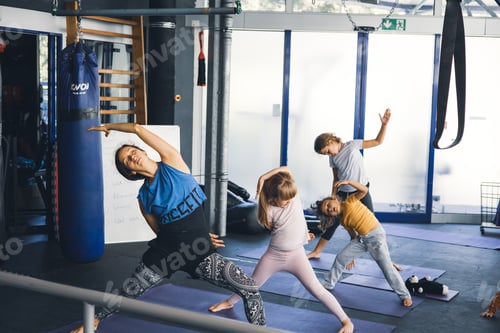 Preview: a young beautiful woman with many children is engaged in yoga with her daughters in the gym,