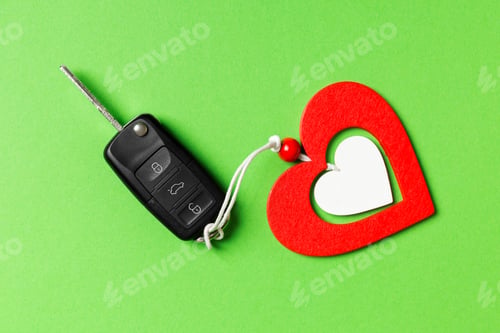 Preview: Top view of car key and wooden heart on colorful background. Luxury present for Valentine's day