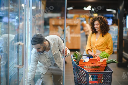 Preview: Couple shopping for groceries in supermarket refrigerator aisle