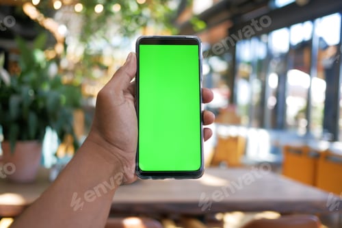 Preview: young man hand using smart phone with green screen at cafe