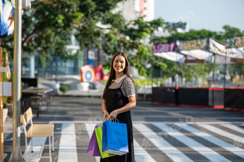 Preview: Young Woman Smiling While Holding Shopping Bags Outdoors