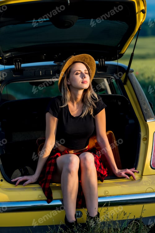 Preview: young woman with hat sits in trunk of car