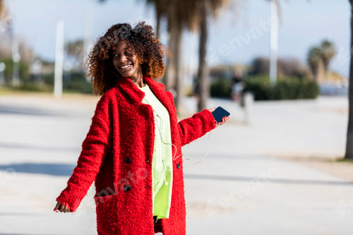 Preview: Young afro american woman laughing while dancing outdoors
