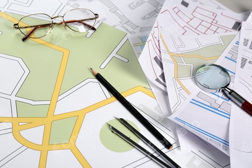 Preview: Office stationery and eyeglasses on cadastral maps of territory with buildings