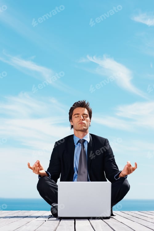 Preview: Business man sitting in lotus position with laptop on a pier