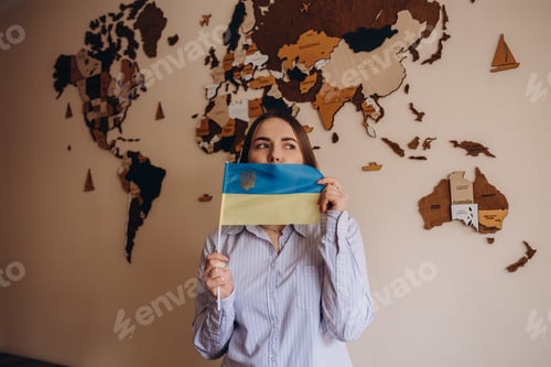 Preview: Woman holding a yellow and blue flag of Ukraine on a background world map