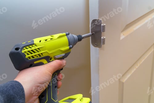 Preview: Hands screwing hinge installation on wooden door with screwdriver