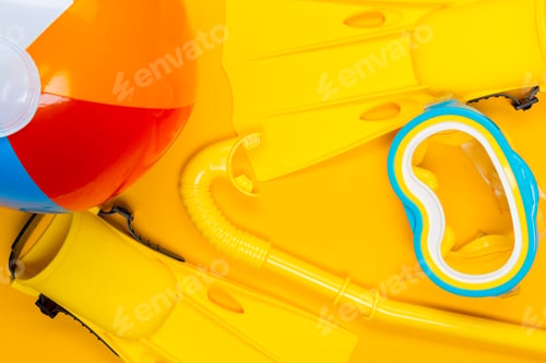 Preview: Colorful beach accessories and snorkeling gear arranged on sunny yellow surface