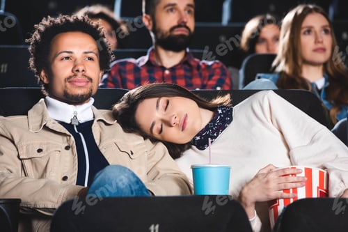 Preview: selective focus of woman sleeping on shoulder of her african american friend in cinema