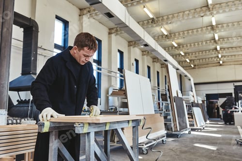 Preview: Busy carpenter in uniform working with wood