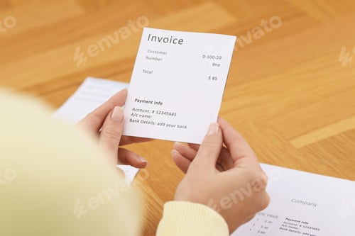 Preview: Paying bills. Woman with different invoices at wooden table indoors, closeup