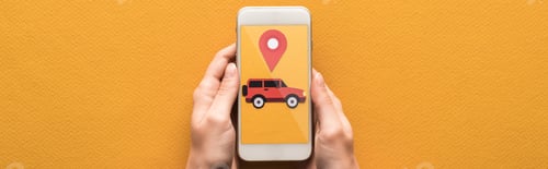 Preview: cropped view of woman holding smartphone with rent car app on orange background, panoramic shot