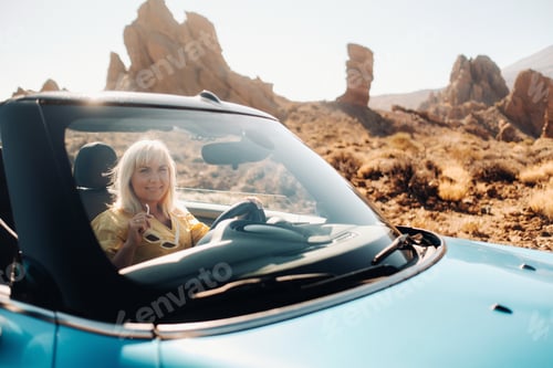 Preview: Girl in yellow dress enjoying a road trip in a convertible through a deserted valley with mountains