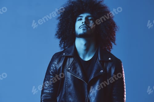 Preview: Portrait of fashion man with curly hair on blue background multinational, colored light, black