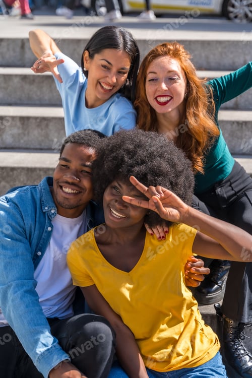 Preview: Happy multiethnic friends sitting on stairs in the city having fun, young models