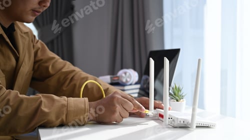 Preview: Close up view of young man connects the internet cable into router wireless at home.