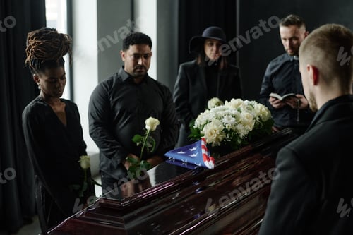 Preview: Diverse Group Mourning at Funeral Service Holding Flowers near Flag Draped Coffin