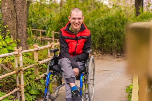 Preview: Portrait of a paralyzed young man in a public park in the city. Sitting in the wheelchair