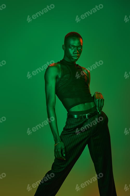Preview: Young man exudes confidence and style against a vibrant green backdrop showcasing modern fashion